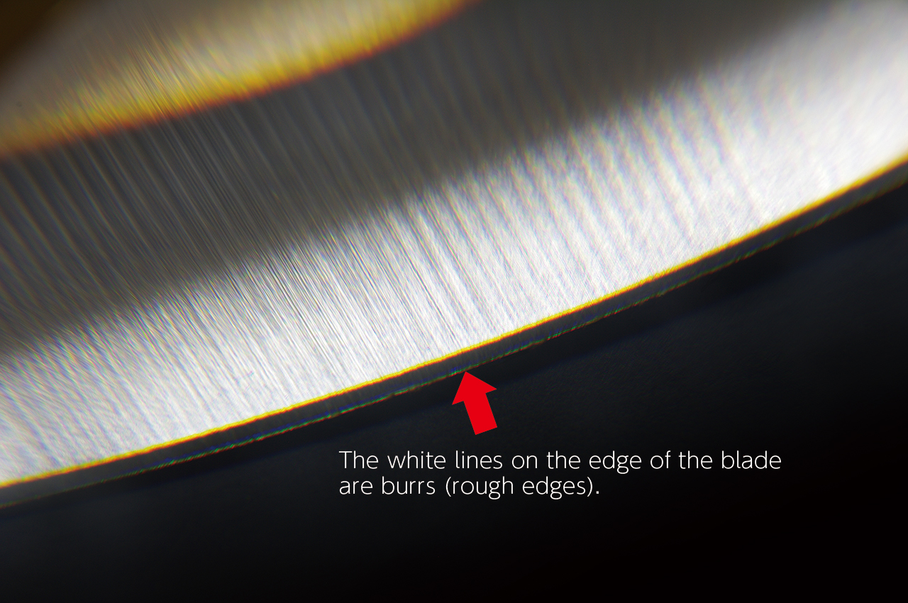 The white lines on the edge of the blade are burrs (rough edges)